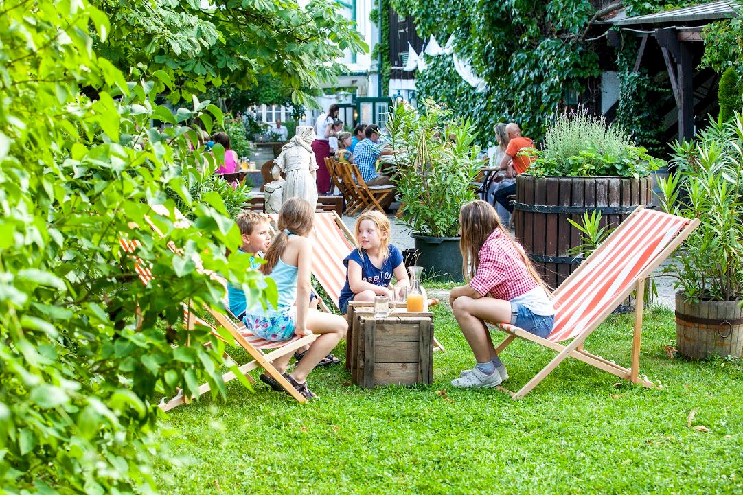 Kinder sitzen auf Liegestühlen im Garten eines Cafés.