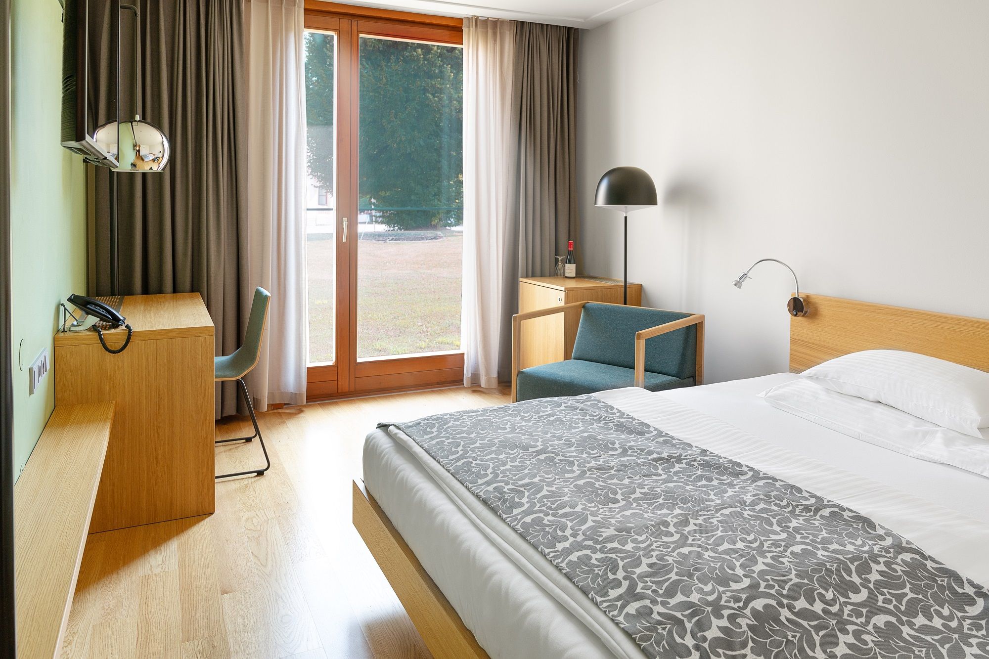 Modernes Hotelzimmer mit Holzmöbeln, großem Fenster und Bett.